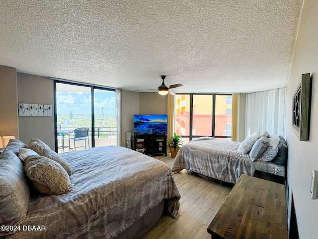 bedroom featuring a textured ceiling, a wall of windows, light hardwood / wood-style flooring, and ceiling fan