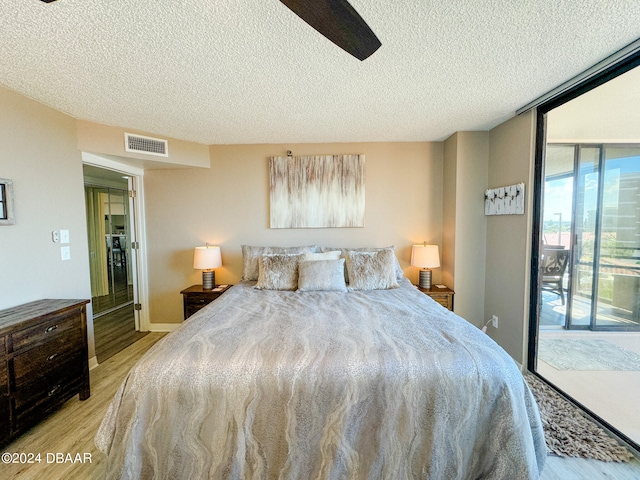 bedroom featuring access to outside, a textured ceiling, and light wood-type flooring