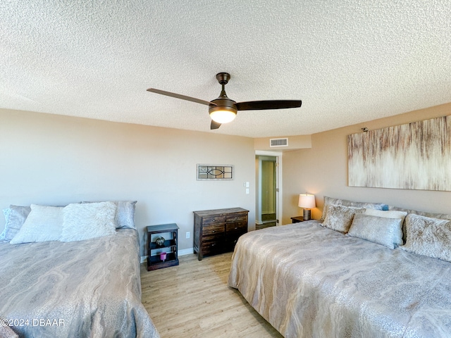 bedroom with light hardwood / wood-style floors, a textured ceiling, and ceiling fan