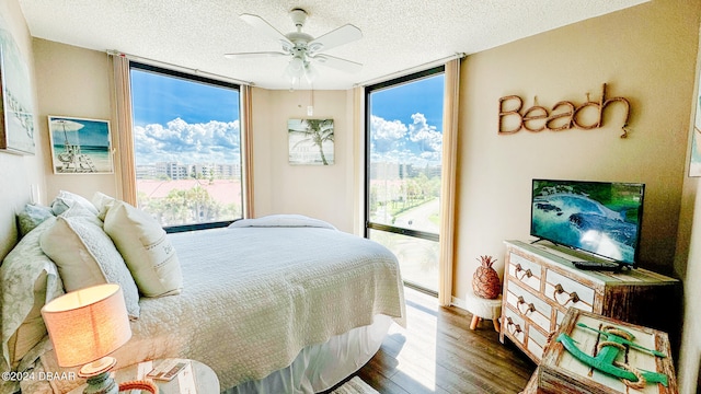 bedroom featuring a textured ceiling, access to exterior, expansive windows, hardwood / wood-style flooring, and ceiling fan