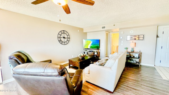 living room with light hardwood / wood-style flooring, a textured ceiling, and ceiling fan