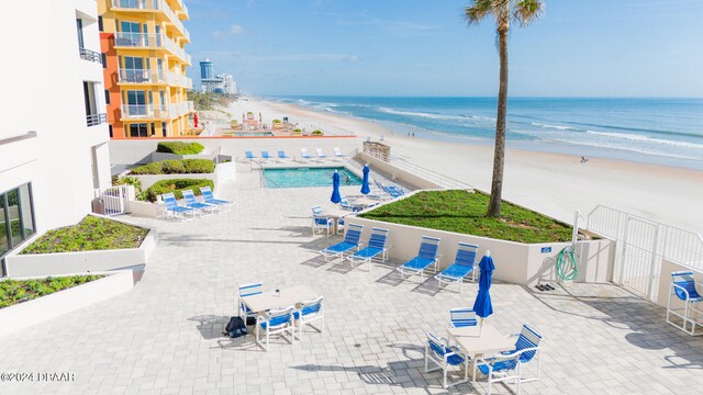 view of swimming pool featuring a beach view, a water view, and a patio area