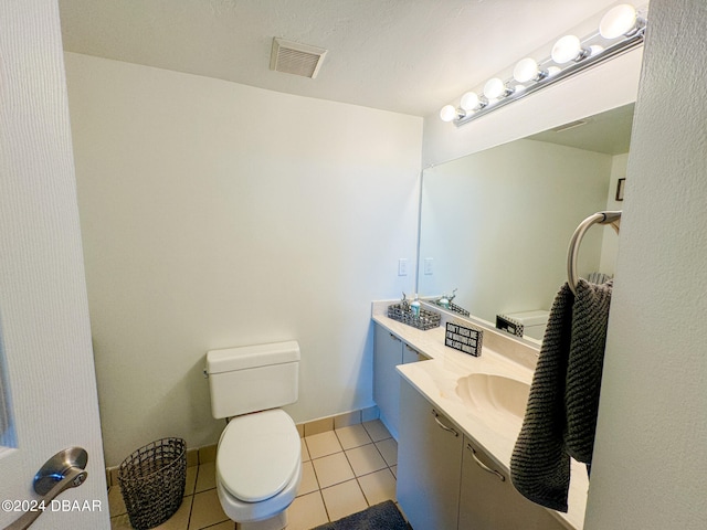 bathroom with toilet, vanity, and tile patterned floors