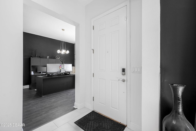 entrance foyer with a chandelier, baseboards, and tile patterned floors