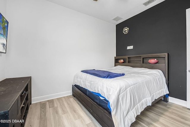 bedroom with wood finished floors, visible vents, and baseboards