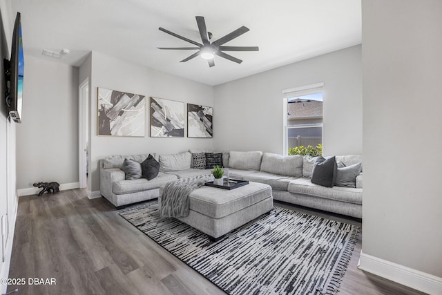 living room with a ceiling fan, baseboards, and wood finished floors