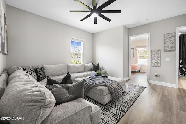 living area with light wood finished floors, ceiling fan, and baseboards