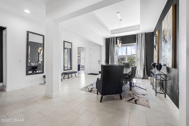 dining room with light tile patterned floors, baseboards, and a tray ceiling