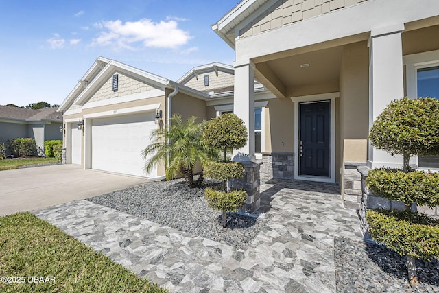 view of exterior entry with an attached garage, stone siding, driveway, and stucco siding