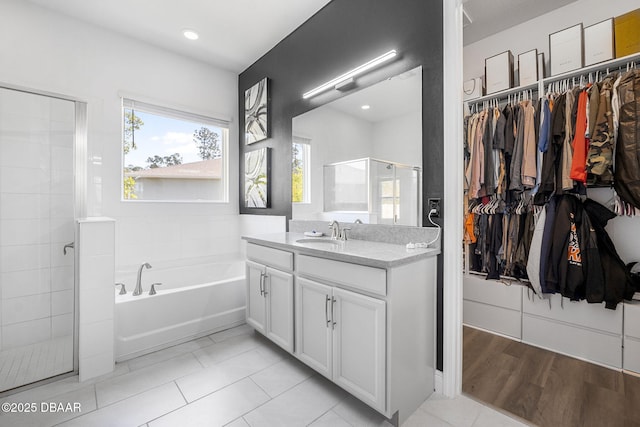 full bath featuring a stall shower, a walk in closet, vanity, and a bath