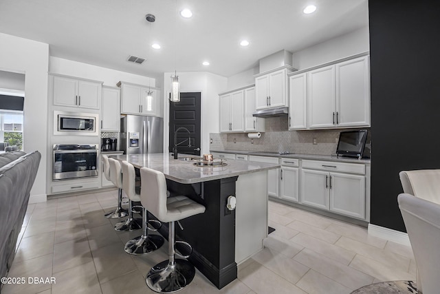 kitchen with visible vents, backsplash, appliances with stainless steel finishes, a sink, and under cabinet range hood