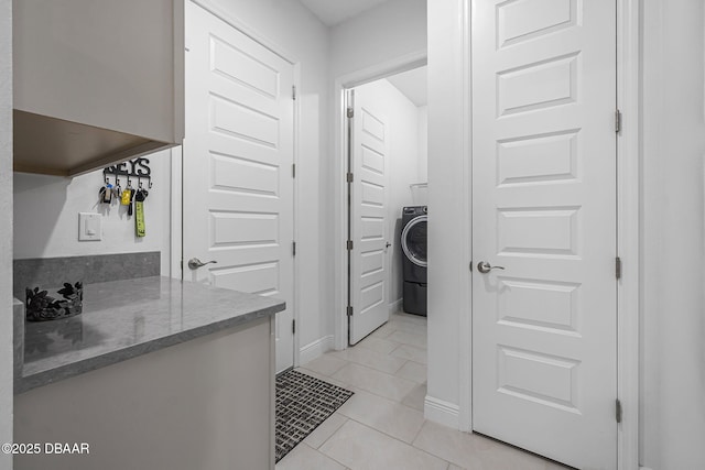 bathroom with washer / clothes dryer, tile patterned flooring, and baseboards