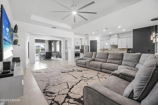 living area with recessed lighting, a raised ceiling, ceiling fan, and light tile patterned floors