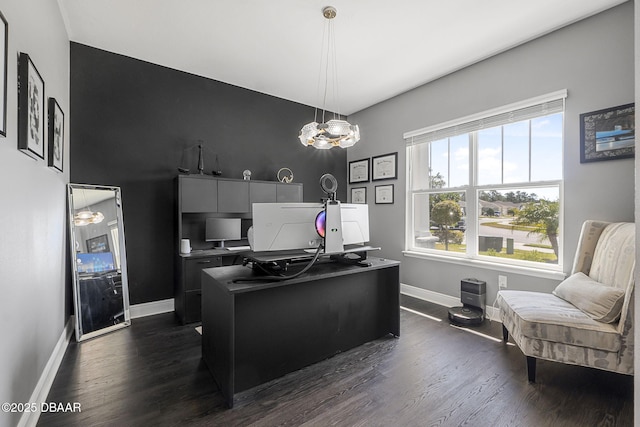 kitchen with baseboards, dark wood finished floors, hanging light fixtures, a kitchen island with sink, and a chandelier