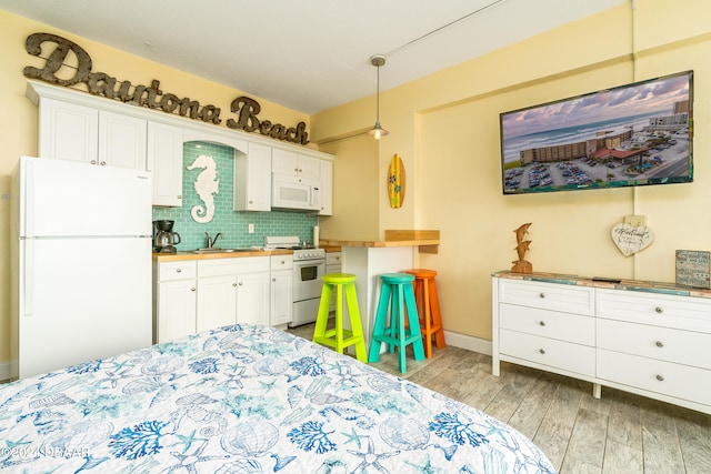 bedroom featuring white refrigerator, sink, and light hardwood / wood-style flooring