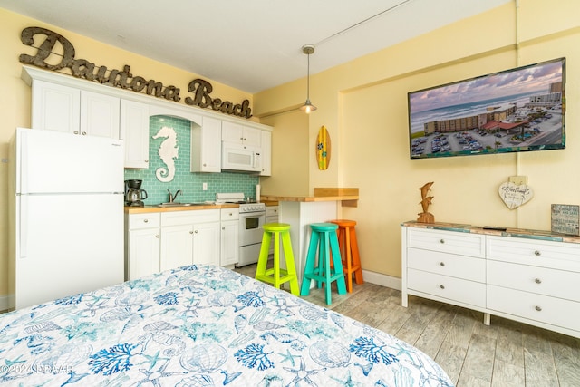 2301 S Atlantic Ave Unit 111, Daytona Beach, FL 32118 - bedroom with freestanding refrigerator, a sink, light wood-style flooring, and baseboards