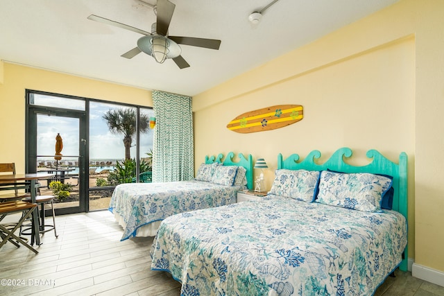 bedroom with ceiling fan, access to exterior, rail lighting, and wood-type flooring