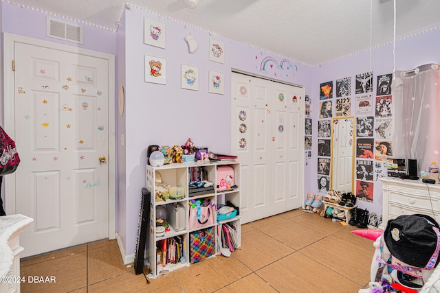 bedroom with a closet, a textured ceiling, and tile patterned floors