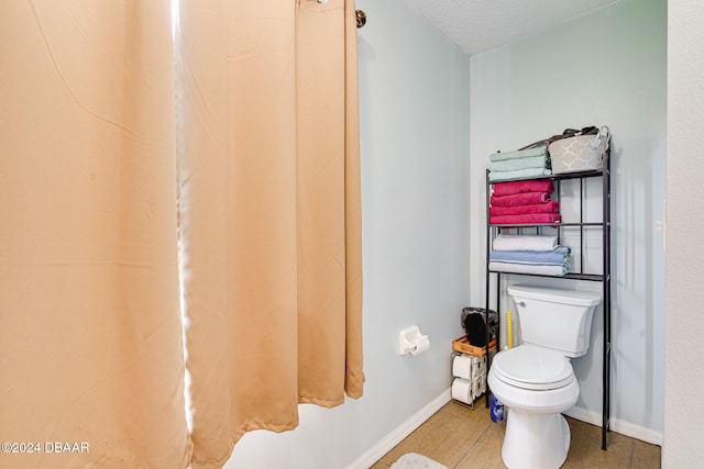 bathroom featuring tile patterned floors, a textured ceiling, and toilet