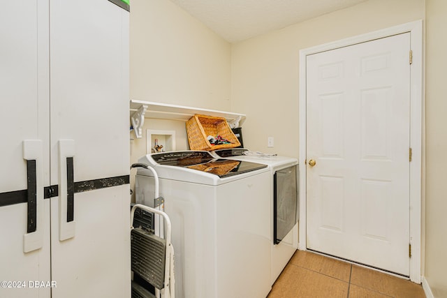 laundry area with a textured ceiling, washing machine and dryer, and light tile patterned floors