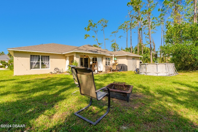 back of property with a lawn, a fire pit, and a patio area