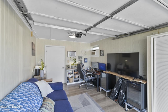 home office featuring a garage, a wall mounted air conditioner, and light wood finished floors