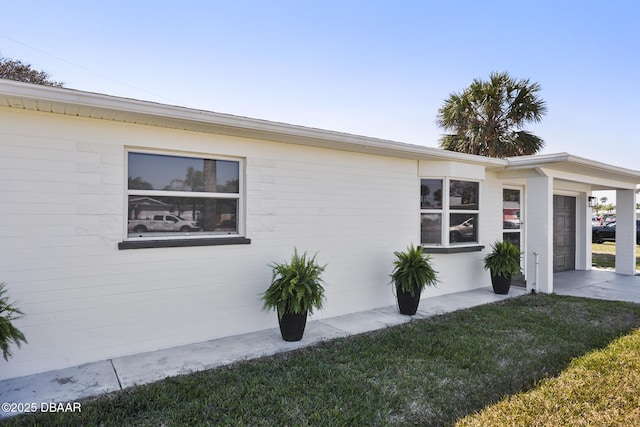 view of side of property with an attached garage, driveway, and a lawn