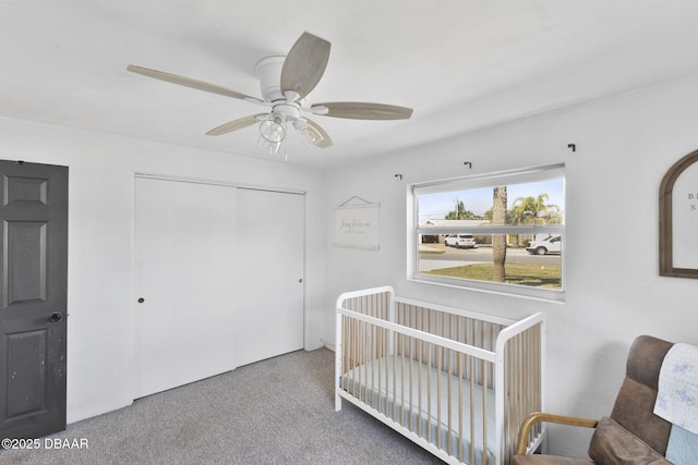 carpeted bedroom featuring a crib, a ceiling fan, and a closet