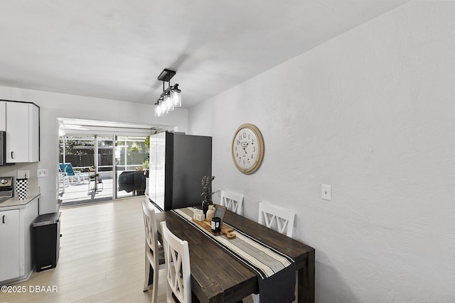 dining room featuring light wood-type flooring and a textured wall