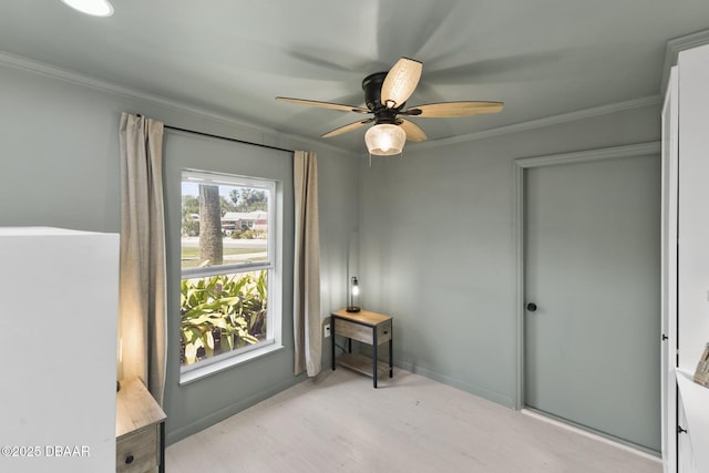 interior space featuring ceiling fan, baseboards, light wood-style flooring, and crown molding