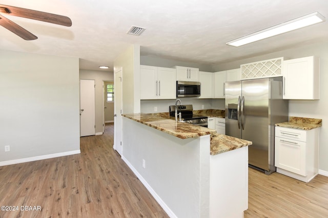 kitchen featuring kitchen peninsula, light stone countertops, white cabinetry, light wood-type flooring, and appliances with stainless steel finishes