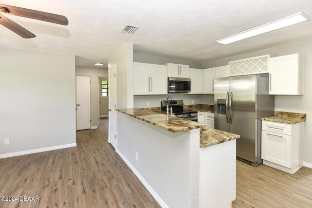 732 Orchard Ave, Ormond Beach, FL 32174 - kitchen with stainless steel appliances, light stone countertops, light wood-style flooring, and a peninsula