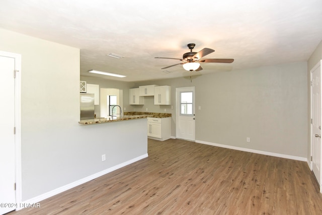 unfurnished living room featuring hardwood / wood-style floors, sink, and ceiling fan