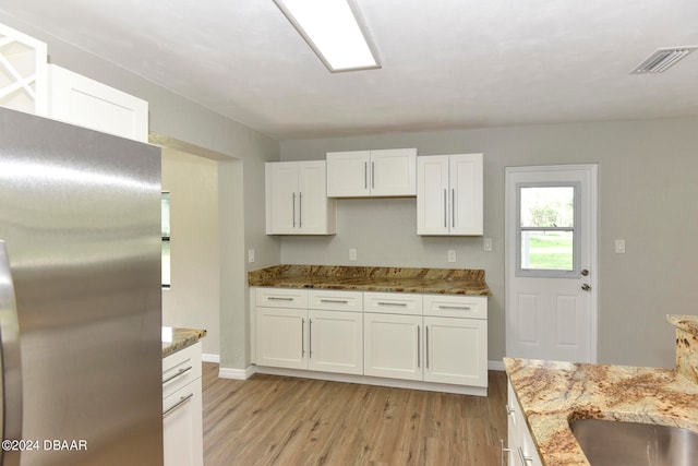 kitchen with white cabinetry, stone counters, stainless steel refrigerator, and light hardwood / wood-style flooring