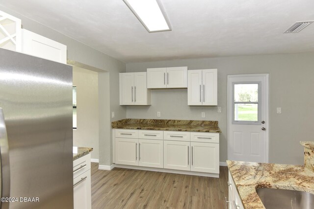 732 Orchard Ave, Ormond Beach, FL 32174 - kitchen featuring freestanding refrigerator, light wood-style flooring, white cabinets, light stone counters, and baseboards