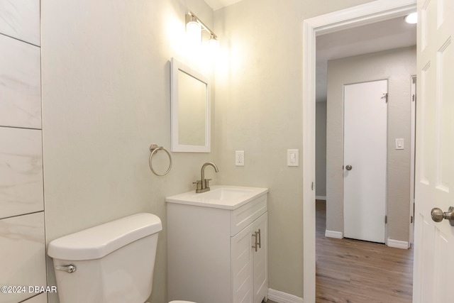 bathroom featuring toilet, vanity, and hardwood / wood-style floors