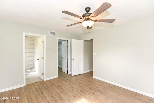 unfurnished bedroom featuring connected bathroom, ceiling fan, a closet, light hardwood / wood-style flooring, and a walk in closet