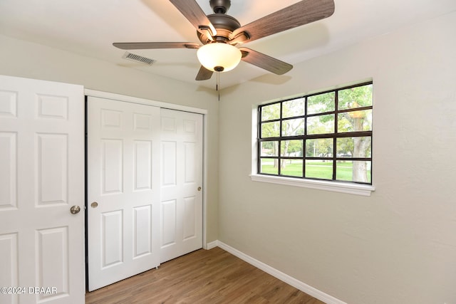 unfurnished bedroom with a closet, hardwood / wood-style flooring, and ceiling fan