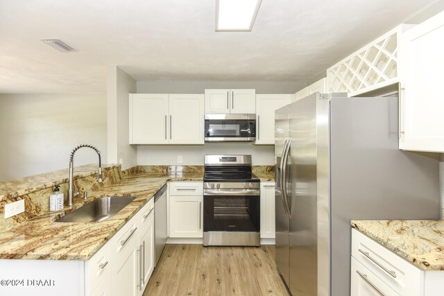 732 Orchard Ave, Ormond Beach, FL 32174 - kitchen featuring stainless steel appliances, a sink, light wood-style floors, light stone counters, and a peninsula