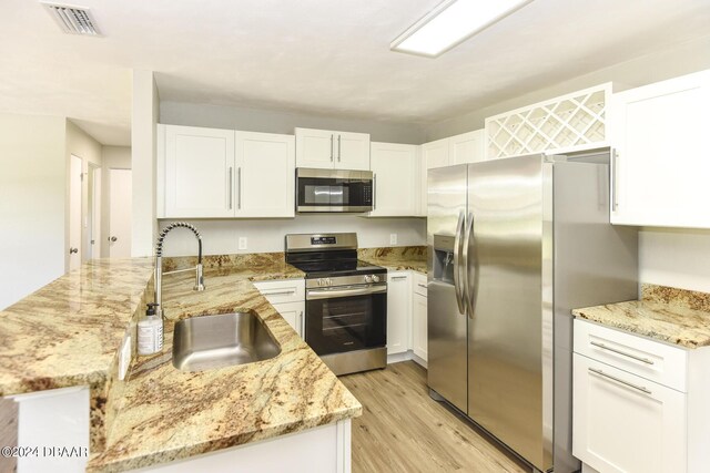 732 Orchard Ave, Ormond Beach, FL 32174 - kitchen featuring stainless steel appliances, a sink, a peninsula, light wood-type flooring, and light stone countertops
