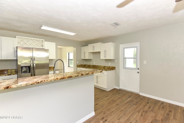 kitchen featuring white cabinets, stainless steel refrigerator with ice dispenser, wood-type flooring, and light stone countertops