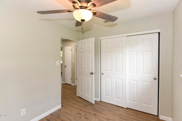 unfurnished bedroom with light hardwood / wood-style flooring, ceiling fan, and a closet