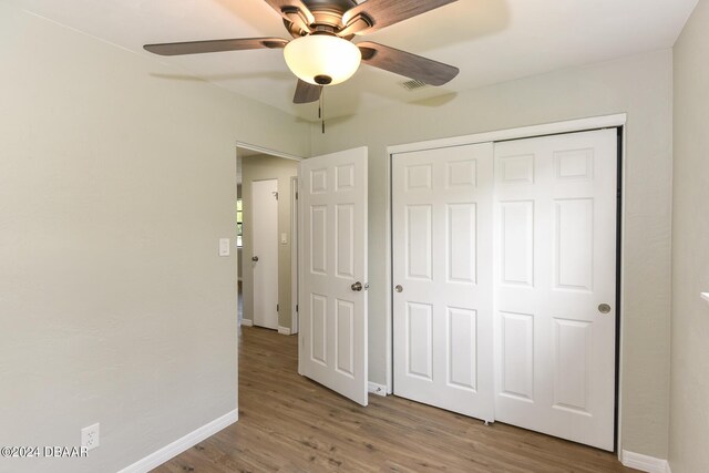 732 Orchard Ave, Ormond Beach, FL 32174 - unfurnished bedroom with wood finished floors, baseboards, a closet, and a ceiling fan