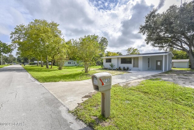 732 Orchard Ave, Ormond Beach, FL 32174 - single story home featuring a front yard, driveway, a carport, and stucco siding