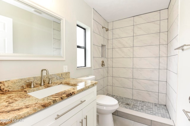 bathroom featuring tiled shower, tile patterned floors, toilet, and vanity