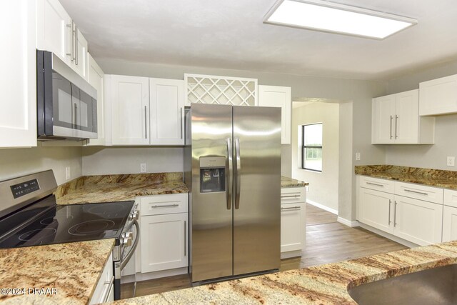 732 Orchard Ave, Ormond Beach, FL 32174 - kitchen with appliances with stainless steel finishes, white cabinets, wood finished floors, light stone counters, and baseboards