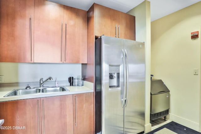 kitchen with light countertops, a sink, stainless steel refrigerator with ice dispenser, and baseboards