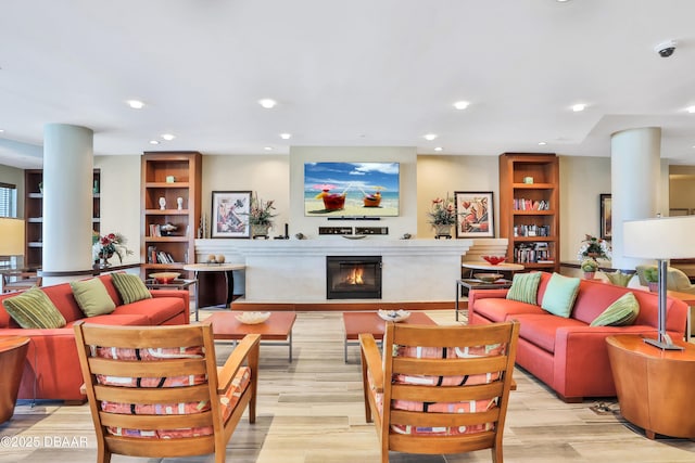 living room with a glass covered fireplace, light wood-style flooring, and recessed lighting