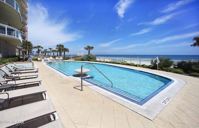 community pool featuring a patio area, fence, and a water view