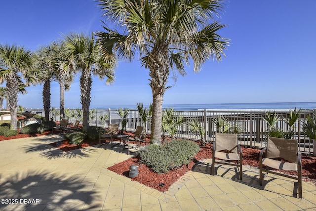 view of patio with a water view and fence